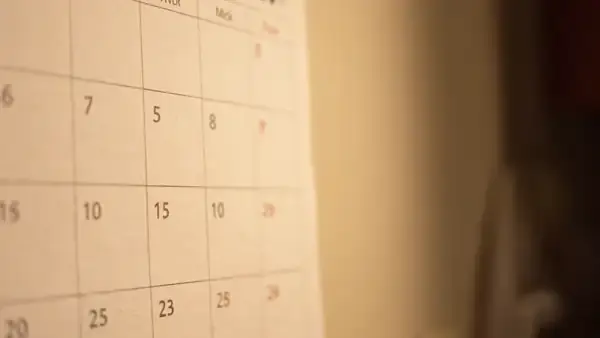 A man's hand ticking off squares on a plain paper calendar with a pencil